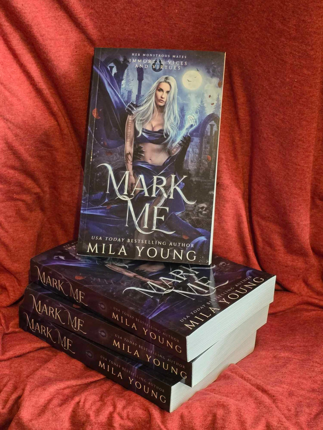 A heavily discounted damaged paperback copy of Mark Me featuring a silver foiled cover, colourful artwork, printed edges, and accompanying character stickers, illustrating a steamy paranormal romance with dark themes, enemies to lovers, and shifter characters