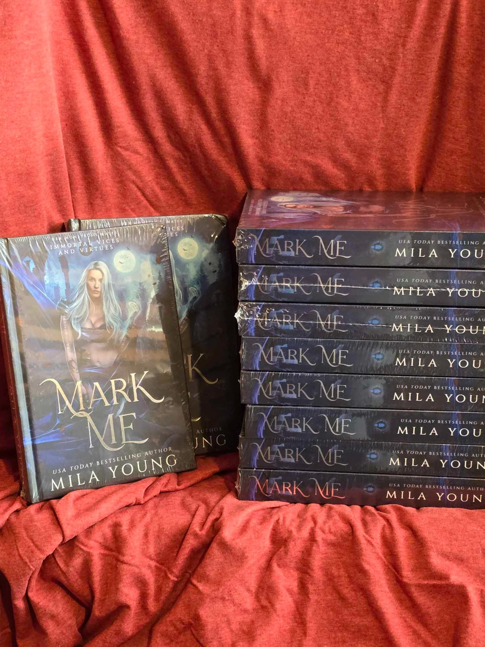 A heavily damaged foil-covered hardback copy of the Mark Me: Special Edition fantasy romance novel, featuring coloured pages, printed edges, exclusive artwork, a foiled bookmark, character stickers, and postcards, illustrating a limited edition paranormal reverse harem with dark themes and intense characters