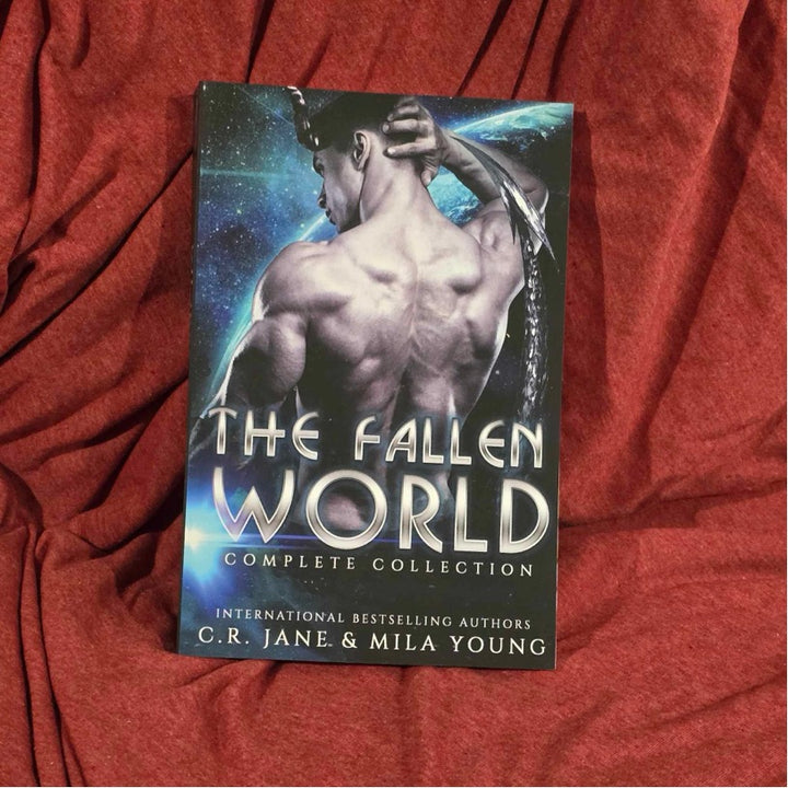 A heavily discounted, damaged US edition of the Fallen World: Complete Series featuring three alien warriors and a human woman, depicting a fiery cover with intense action and romance themes, including four full-length books of alien invasion, heart-pounding scenes, and a guaranteed happy ending